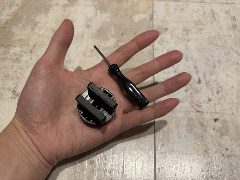 SwitchBot ロックProのサムターンアダプターと付属ドライバーを手のひらに載せた様子